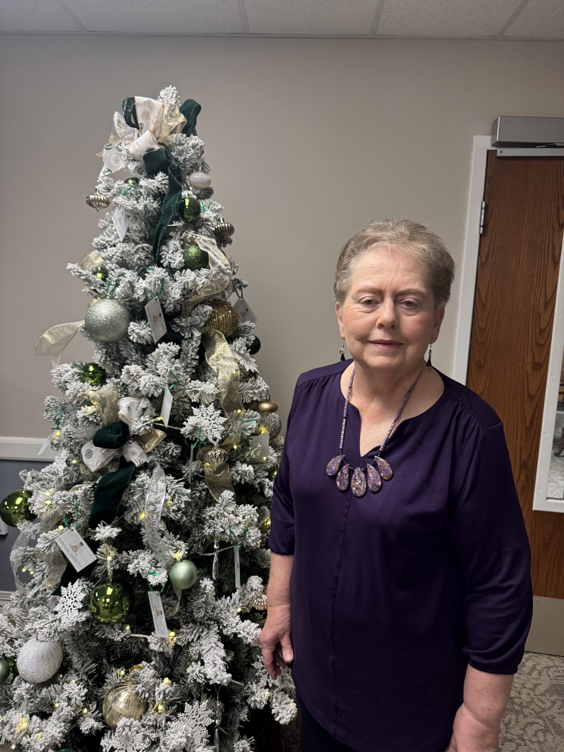 Woman posing next to a decorated Christmas tree, facing the camera