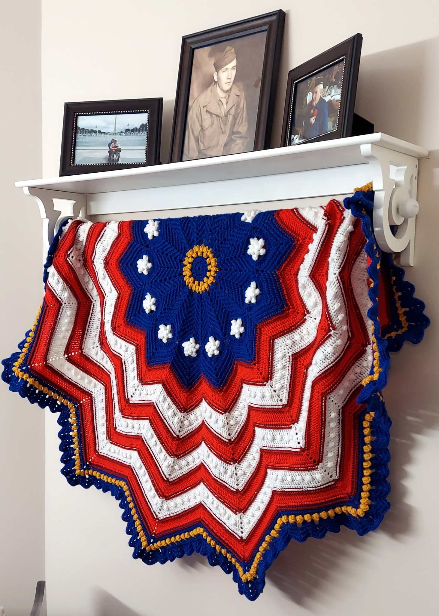Photo of shelf with pictures and a crocheted US flag hanging